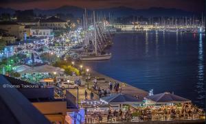ミティカスにあるVilla Nafsikaの夜の水辺の桟橋に立つ群衆