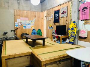 een kamer met een tafel en een bureau met een surfplank bij Matsukaze The Guest House Ishigaki in Ishigaki Island