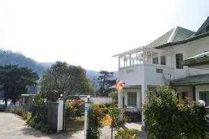 a white house with a fence in front of it at Samri Holiday Bunglow in Nuwara Eliya