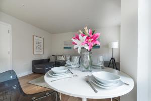 a white dining room table with a vase of flowers on it at Hampden Apartments - The Diana in Windsor