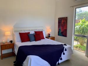 ein Schlafzimmer mit einem großen Bett mit roten und blauen Kissen in der Unterkunft Wilderness House in Margaret River Town