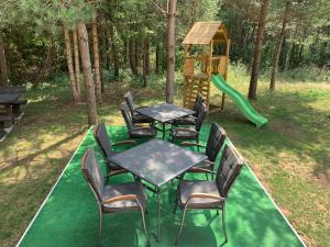 a set of tables and chairs with a playground at Apartmani Zeder Plitvička jezera in Rudanovac