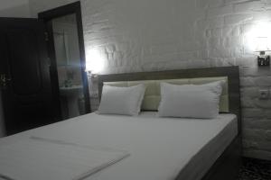 ein Bett mit weißen Laken und Kissen in einem Schlafzimmer in der Unterkunft Orient Star Hotel in Taschkent