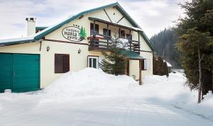 a building with a green garage in the snow at Vila Maria Rustic Predeal in Predeal