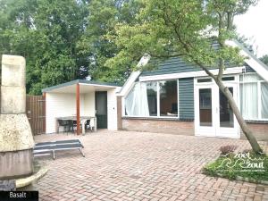 una casa con un banco delante de ella en Holiday Home BASALT 6 p Amsterdam and the beach, en Opmeer