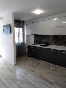 a kitchen with white cabinets and a wooden floor at Apartament CAMEL in Eforie Nord