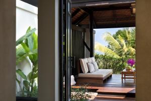 a porch with a white couch on a wooden deck at Anantara Lawana Koh Samui Resort in Chaweng