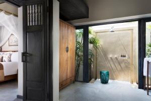 a bedroom with a door open to a bedroom with a bed at Anantara Lawana Koh Samui Resort in Chaweng