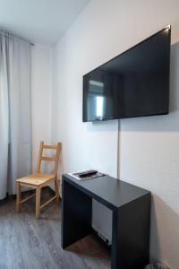 a room with a desk with a television on a wall at Hotel Central in Menden