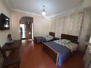 a room with two beds and a tv and a desk at Hotel Selika in Rustavi