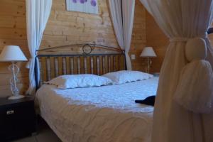 a bedroom with a bed with white sheets and two lamps at le chalet du roc in La Panouse