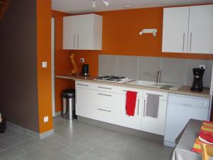 ô zirondels في La Vernelle: مطبخ مع دواليب بيضاء وجدار برتقالي
