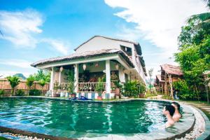 un hombre y una mujer en una piscina frente a una casa en Nan House - Tam Coc en Ninh Binh