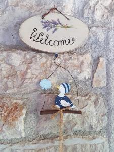 un adorno de pájaro colgando de una pared con la palabra bienvenida en FUNTANA-MIA ROOMS B&B, en Funtana