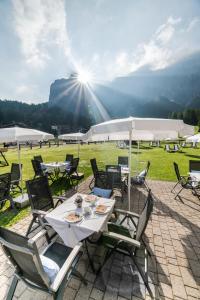 a group of tables and chairs with the sun shining at Hotel Fil Da Mont in Selva di Val Gardena