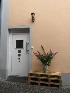Beim Wegmacher في Rennertshofen: باب مع مزهرية من الزهور بجوار مبنى
