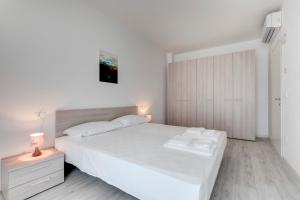 a white bedroom with a large white bed and a cabinet at Venice Golf residence in Venice-Lido