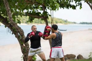 two men are standing on the beach with boxing gloves at Anantara Lawana Koh Samui Resort in Chaweng