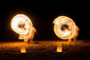 two people standing in the sand with a fire show at Anantara Lawana Koh Samui Resort in Chaweng