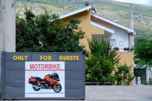 a sign in front of a house with a motorcycle on it at Pansion Rose in Mostar