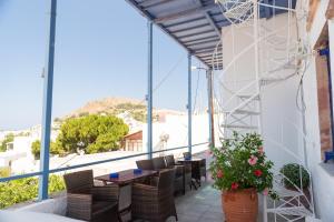 a balcony with tables and chairs and a large window at El Greco Studios in Patmos