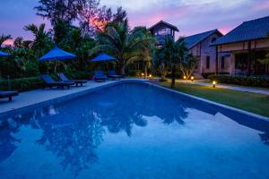 a villa with a swimming pool at night at Na Vela Village - Adults Only Hotel in Ko Lanta