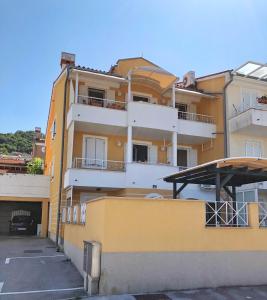 ein gelbes Gebäude mit Balkon und Parkplatz in der Unterkunft Villa Moare in Koper