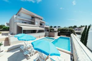 a villa with a swimming pool and two blue umbrellas at Apartments Prestige Petrcane 1 in Petrcane