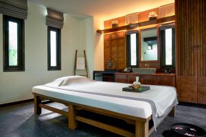 a bedroom with a bed and a sink and a mirror at Anantara Lawana Koh Samui Resort in Chaweng