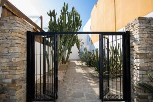 a black iron gate in a courtyard with plants at Hostal Doña Lola Marina in Zahara de los Atunes