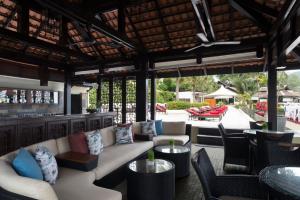 a patio with a couch and tables and chairs at Anantara Lawana Koh Samui Resort in Chaweng