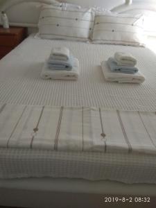 Una cama con toallas blancas y almohadas. en KROKOS HOUSE en Aliveri