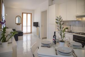a white kitchen with a table with plates on it at DELPOSTO Marina di Ragusa SR in Marina di Ragusa +46 photos