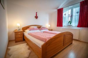 Schlafzimmer mit einem Bett und einem Fenster mit roten Vorhängen in der Unterkunft Landhaus Bellamontes in Leutasch