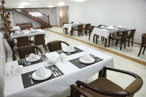 une salle à manger avec des tables et des chaises blanches dans l'établissement Hotel Vardonze, à Boukhara
