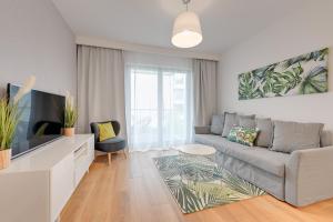 a living room with a couch and a tv at Wave Apartments - Nadmorze in Gdańsk