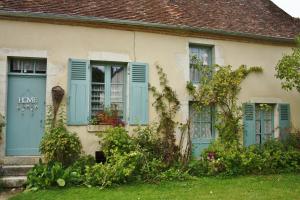 an old house with blue shutters and flowers at petite maison berrichonne in Chârost