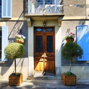 une porte avec deux plantes en pot devant un bâtiment dans l'établissement Papilio, à Montauban-de-Luchon