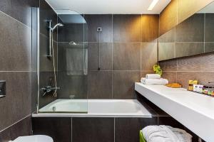 a bathroom with a tub and a toilet and a sink at Skiathos Palace Hotel in Koukounaries