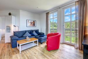 a living room with a blue couch and a red chair at Residenz am Balmer See - BS 52 mit Wellnessbereich in Balm