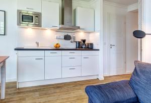 a kitchen with white cabinets and a blue couch at Residenz am Balmer See - BS 52 mit Wellnessbereich in Balm