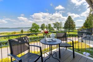 d'une table et de chaises sur un balcon avec vue sur l'eau. dans l'établissement Residenz am Balmer See - BS 52 mit Wellnessbereich, à Balm