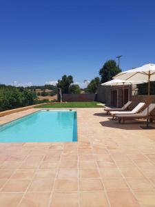 a swimming pool with two lounge chairs and an umbrella at La Codina in San Bartolomé del Grau