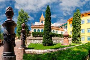 a large yellow building with trees in front of it at HeuReka Apartman in Pécs