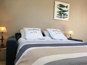 ein Schlafzimmer mit einem Bett mit weißen Laken und Kissen in der Unterkunft PETIT STUDIO de L'ERMITAGE in Gujan-Mestras