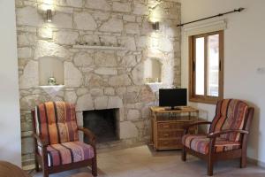 een woonkamer met 2 stoelen en een stenen open haard bij Akourdalia Villas in Pano Akourdalia