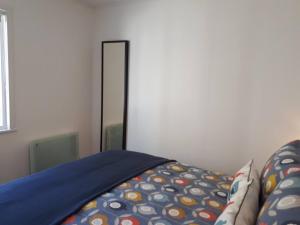 a bed with a blue comforter and a mirror at The Cabin at No 45 in Ballater