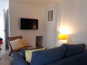 The Cabin at No 45 في بالاتر: غرفة معيشة مع أريكة زرقاء وتلفزيون على الحائط