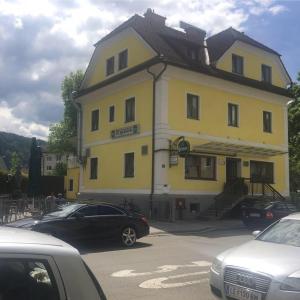 a yellow building with cars parked in front of it at Gasthof Knezevic in Leoben