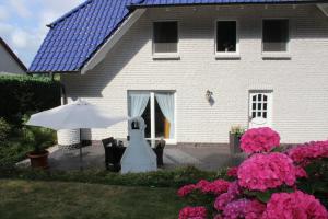 a white house with an umbrella and pink flowers at Ferienwohnung Holzerland in Patzig